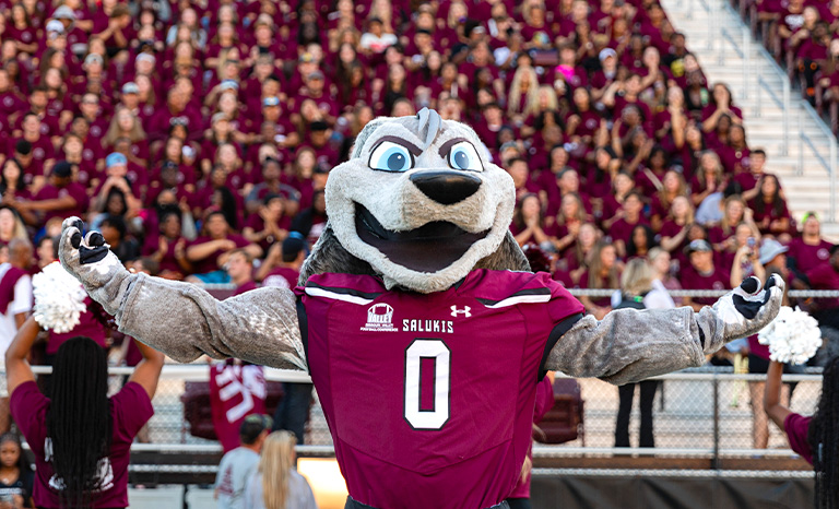 Saluki mascot standing in front of a large crowd of siu students